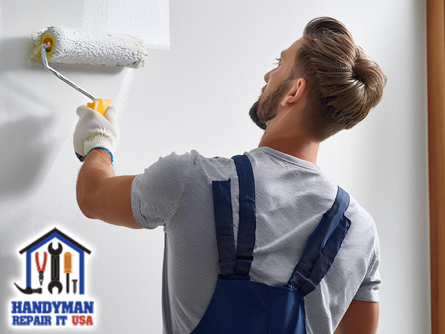 handyman applying fresh coat paint on wall with roller