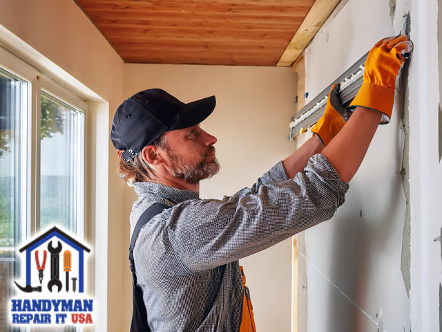 male professional handyman working on comprehensive drywall repair and installation of residential home